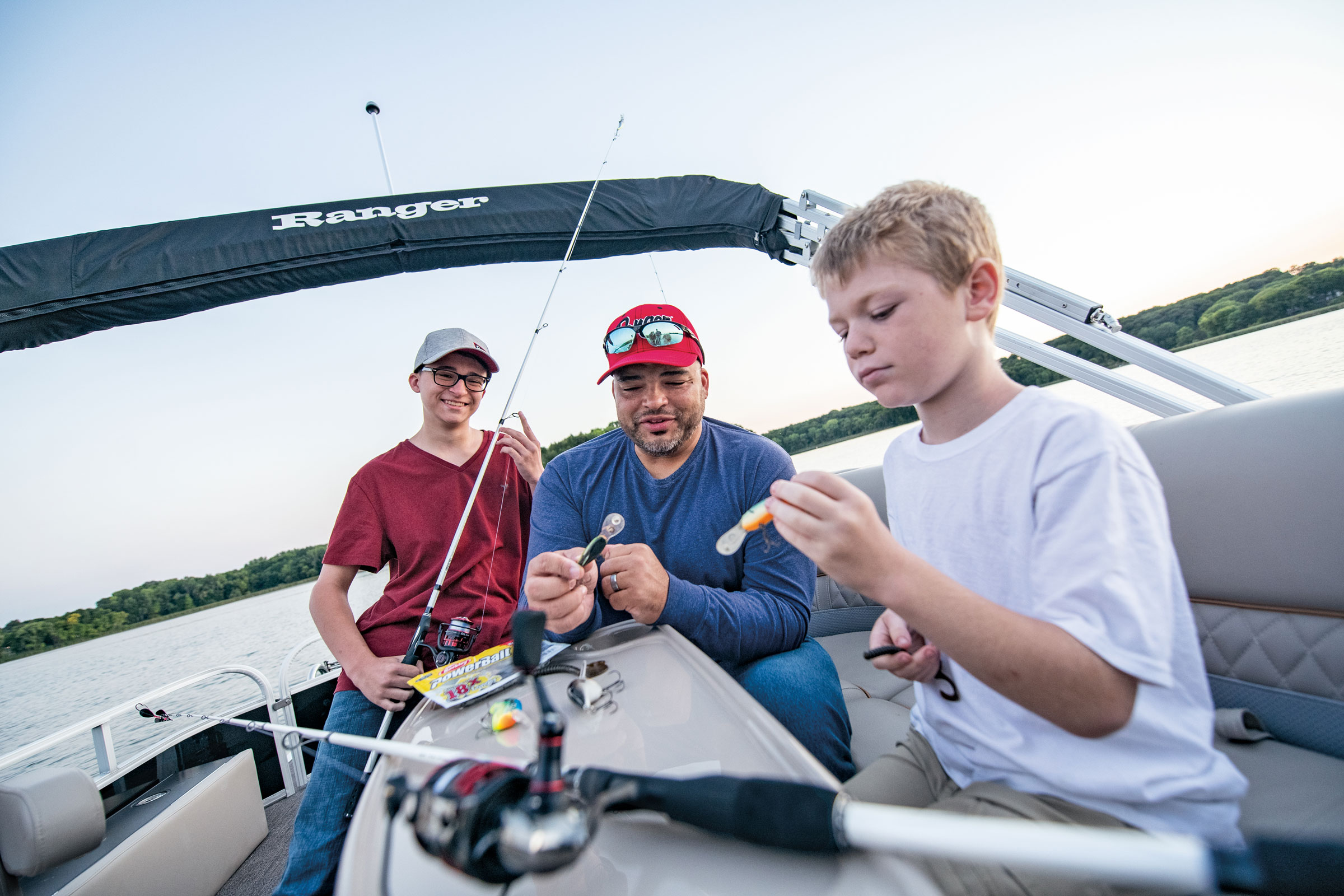 2 kids preparing to fish with help from an adult